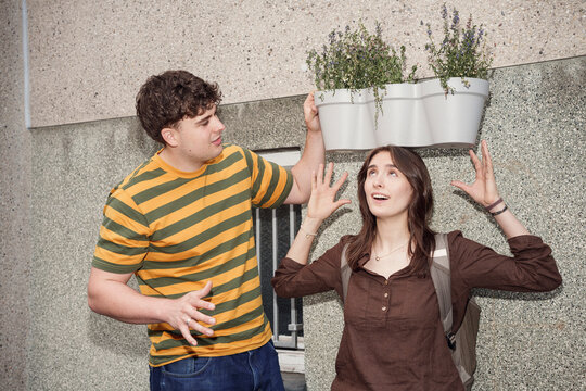 Man holds a flower pot like a crown over a woman