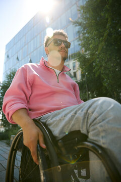Man in a wheelchair navigates a sunny city street