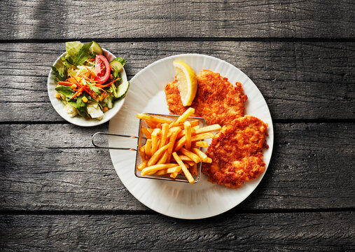 A plate features chicken schnitzel with potato and fresh salad