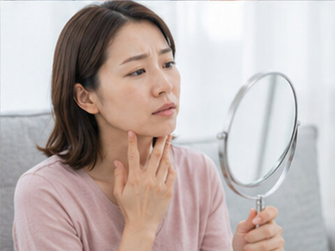 鏡を見る女性,美容,美容医療,肌悩み,顔の悩み,コンプレックス,鏡,女性,日本人女性,顔,肌,頬,目元,口元,鼻,額,あご,フェイスライン,しわ,たるみ,シミ,毛穴,ニキビ,くすみ,乾燥肌,ほうれい線,目の下のクマ,肌荒れ,肌トラブル,スキンケア,エイジングケア,アンチエイジング,美容相談,美容カウンセリング,美容クリニック,美容皮膚科,美容外科,施術前,セルフチェック,確認,悩む,考える,不安,