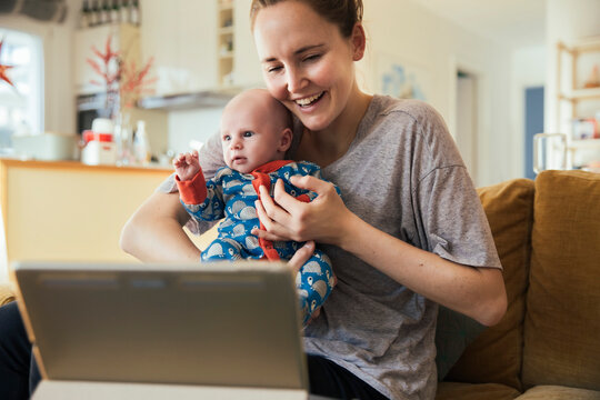 Mother and newborn baby taking a video call at home