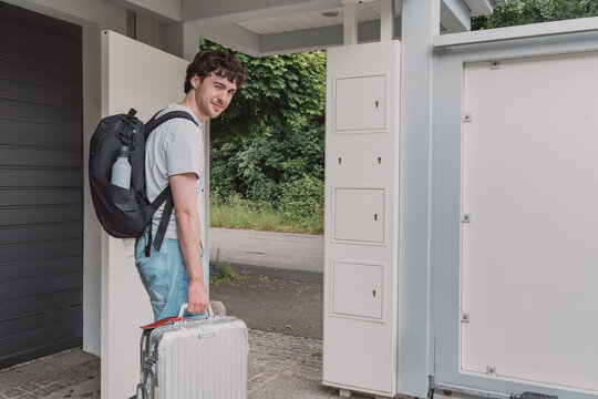 Young man leaves home with a suitcase for a trip
