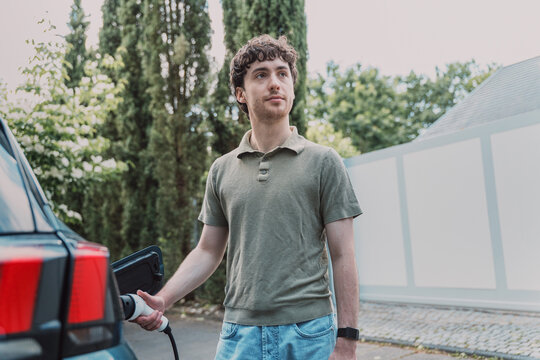 Young man is charging his electric vehicle at home in Germany