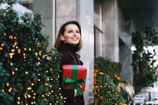 Happy woman holds a Christmas gift outdoors in the city