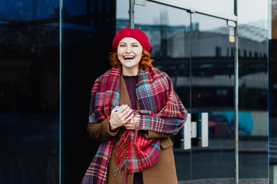Laughing woman holding phone outdoors during winter holiday shopping