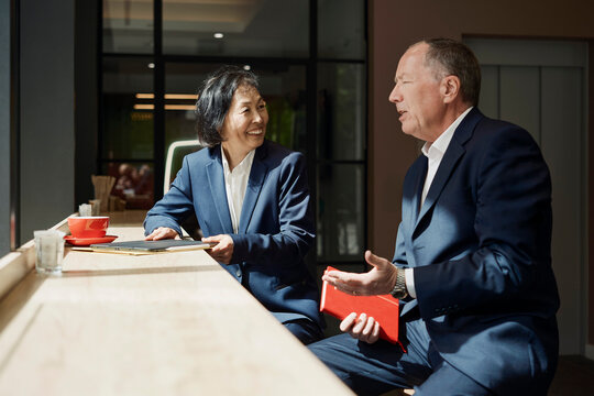 Businessman and businesswoman discuss reports in a coffee shop