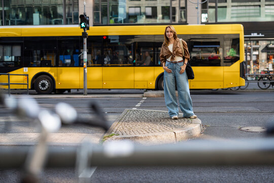 Woman waits at a pedestrian crossing in Berlin during her commute