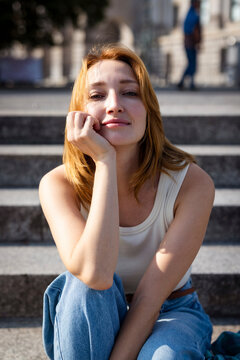 A smiling woman relaxes on a stone step in Berlin