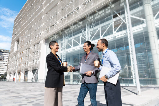 Business people shake hands outside a modern office building