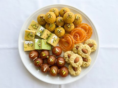 Assorted traditional Indian sweets arranged on a white plate for celebration