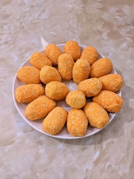 Breaded croquettes arranged on a white plate, viewed from above. Crispy golden coated snacks prepared for frying, suitable for food, cooking, homemade meal, and appetizer concepts