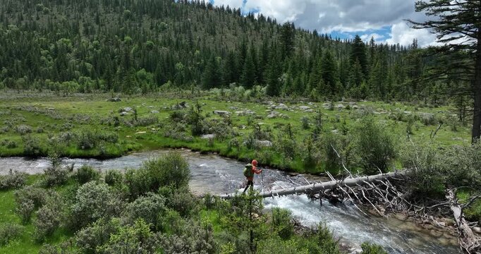 Woman walking on a one plank bridge in high altitude mountains