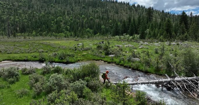 Woman walking on a one plank bridge in high altitude mountains