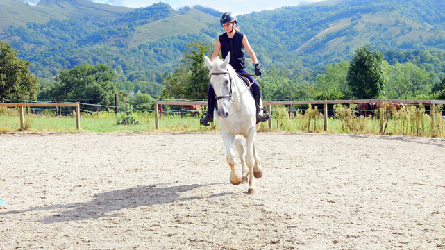 Beautiful young girl on a white horse at an equestrian farm
