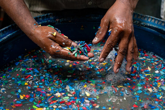 Hands washing shredded plastic at a Dharavi recycling workshop