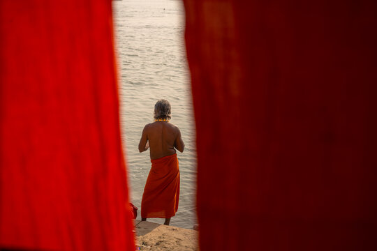 Person at the Ganges framed by red hanging fabric in Varanasi