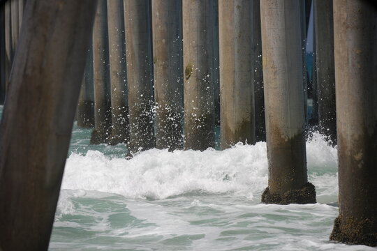 Large waves in the ocean breaking on the pier pylons and barnacles