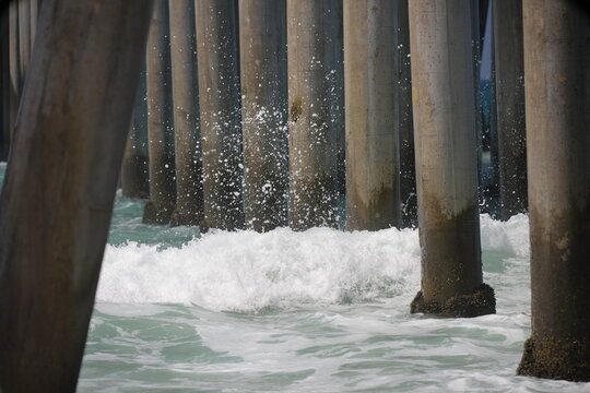 Large waves in the ocean breaking on the pier pylons and barnacles