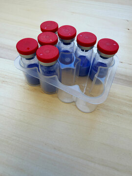 GHK-Cu, copper tripeptide in a vial and bacteriostatic water on a wooden background.