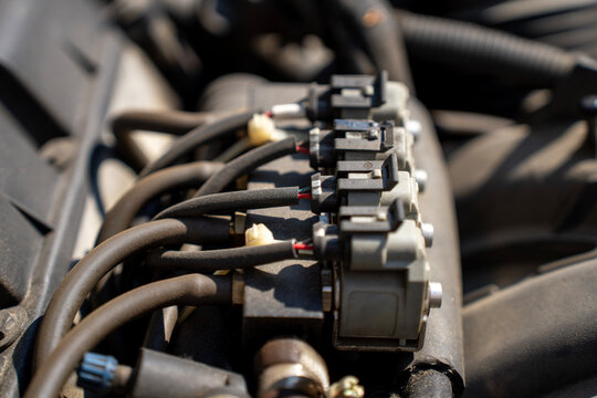 Row of gas fuel injectors on a common rail with rubber tubes and wire plugs mounted on a modern car internal combustion engine.
