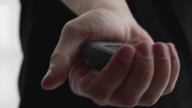 A man squeezes a rubber forearm exerciser with his hand.