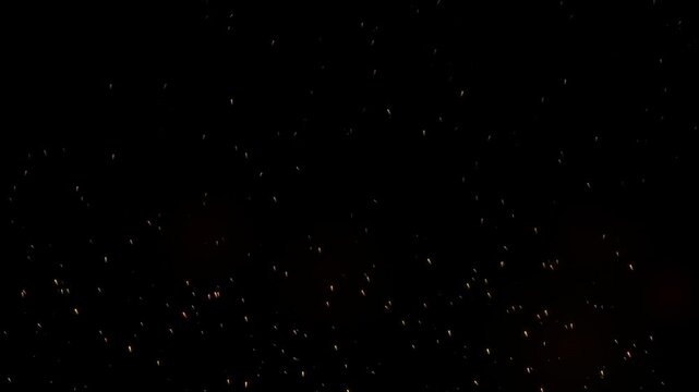 Glowing fire sparks floating in dark night, abstract burning embers overlay for cinematic effects