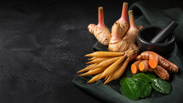 Fresh galangal turmeric and aromatic roots with mortar