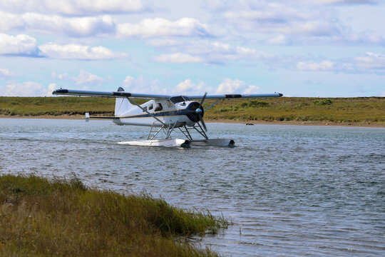 A floatplane rests on calm water near the Egegik River in Alaska, ready for bush travel across remote tundra under partly cloudy sky.