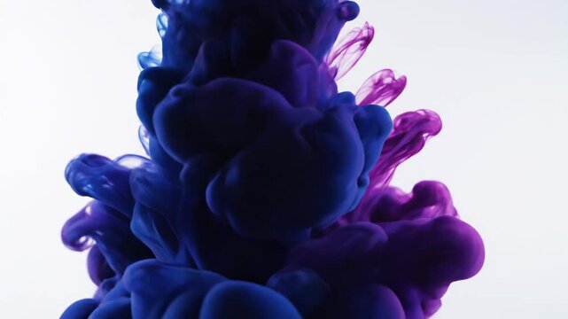 Blue and purple ink clouds swirling and dissolving in clear water