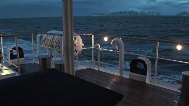 Golden or soft polar light reflects across the Arctic Ocean during a ship voyage, revealing ripples, open water, and the distant northern horizon. The source identifies the location near Norway.