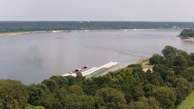 Aerial of industrial riverfront area at Ohio and Mississippi river confluence in Cairo Illinois with train running parallel to the riverbank and barges on the water