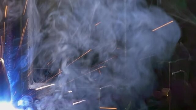 A robotic argon welding arm joins metal pipe sections with controlled motion during an industrial welding process. Bright sparks flare around the welding area as the process continues.