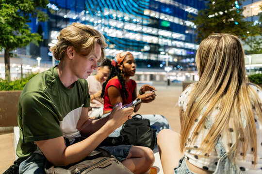 Young diverse friends socializing outdoors at night