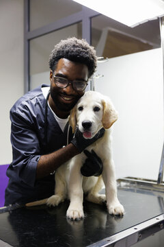 Portrait of young black smiling male doctor embracing dog on leash