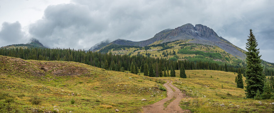 Mountain peak with overcast skies and dirt road