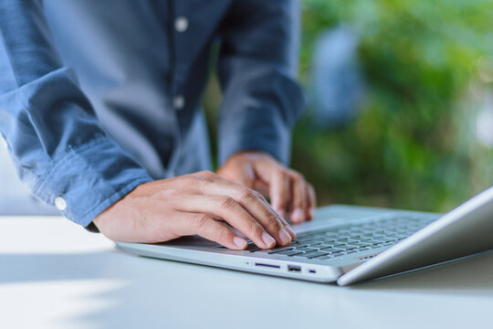 Businessman Leaning Over Laptop Keyboard at Workspace - Agile Working, Standing Desk Productivity, Quick Data Audit, Flexible Work Environment, and Modern Executive Concept