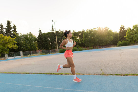 Female athlete running on sports track during evening training