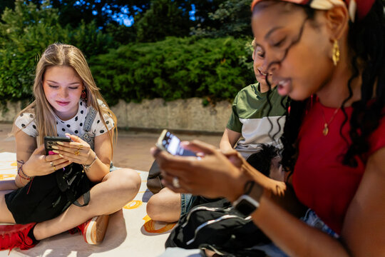 Diverse young people focused on their smartphones outdoors