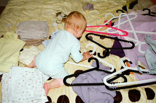 Baby plays with hangers on a bed