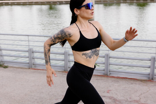 A female athlete running solo by a park lake during the morning