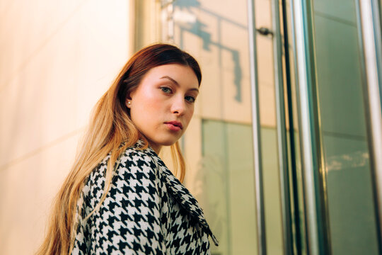 Businesswoman in houndstooth coat looking at camera