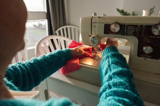 Senior woman sewing fabric with sewing machine at home