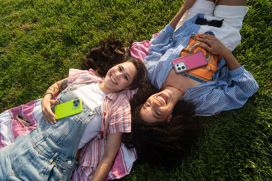 Friends Relax on a Blanket with phone on a Park