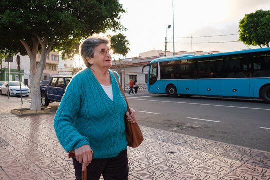 Senior woman walking city street with cane