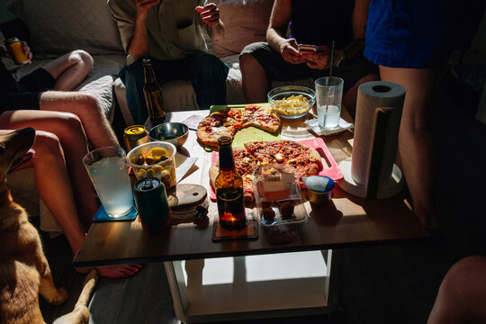 Friends eating pizza during a casual gather with a pet dog