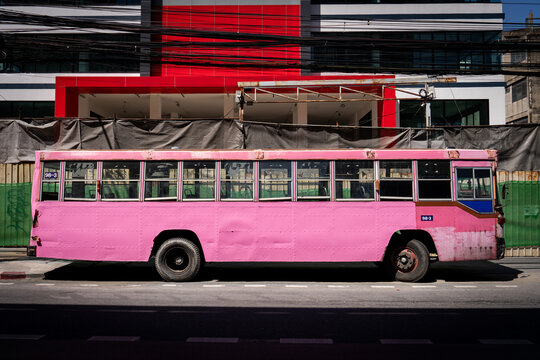 Portrait of a broken down hot pink bus on the street in Bangkok