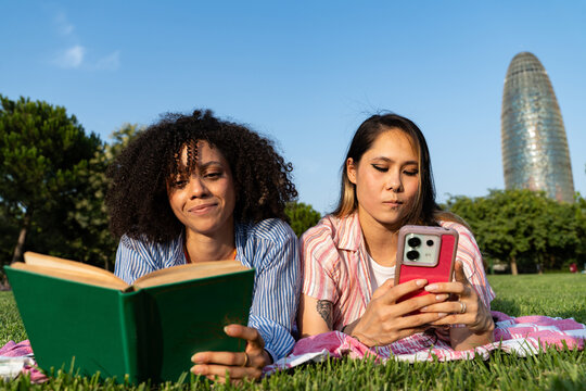 Friends Relax in a Park in Barcelona, Enjoying Books and Phones