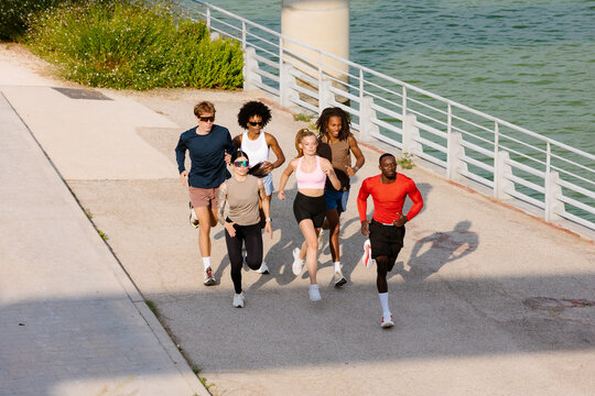 A team of runners training together, jogging alongside a lake
