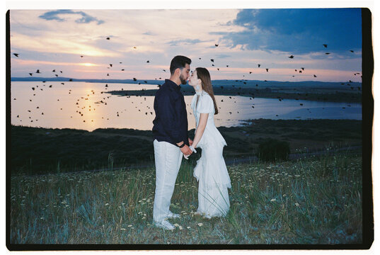 Romantic Couple Kissing by the Lake at Sunset with Birds in Flight