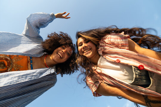 Friends Smiling Under  Blue Sky With Arms Raised